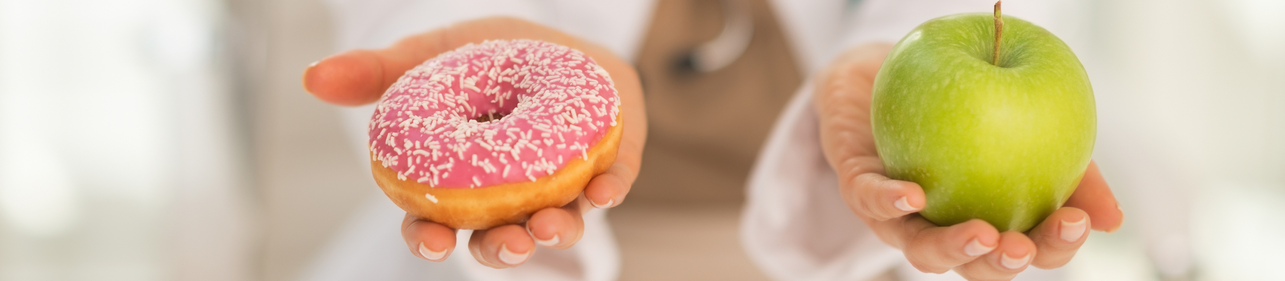 Krupni plan na doktoricu koja nudi izbor između jabuke i krofne