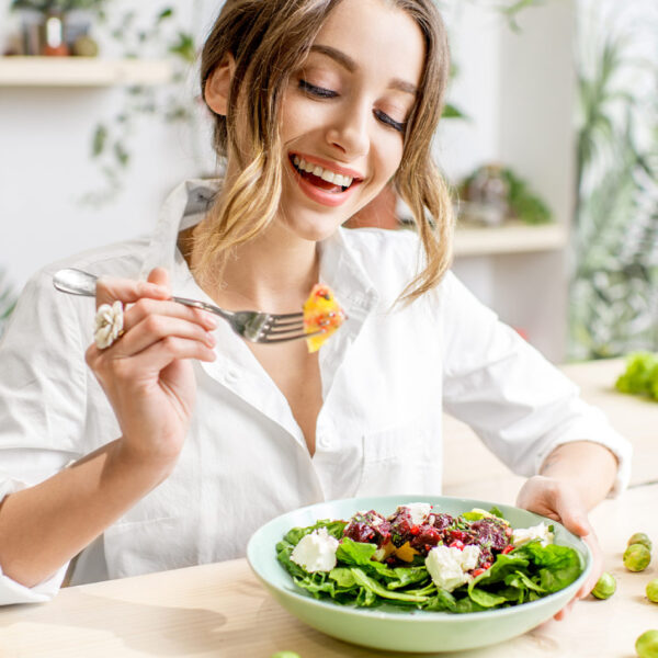 Nasmijana žena jede zdravu salatu za stolom