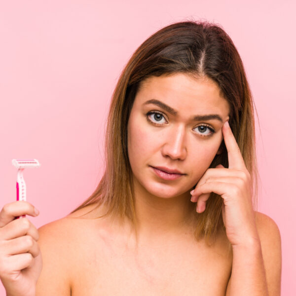 Mlada žena drži britvu i izgleda zabrinuto